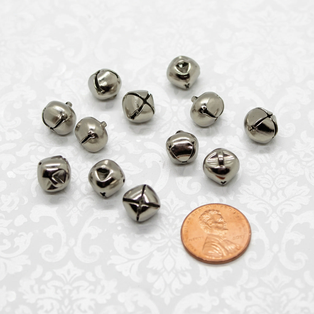 Small metal bells with a penny for scale on a white background