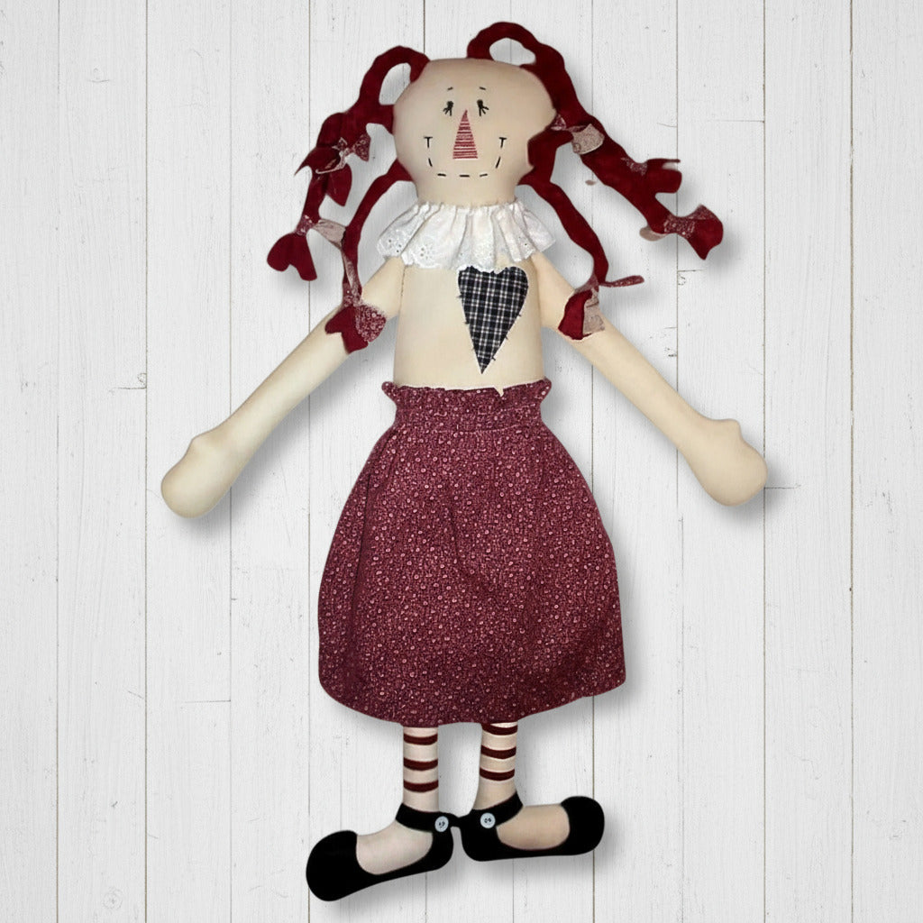Vintage-style doll with red hair, checkered shirt, and maroon skirt on a white background