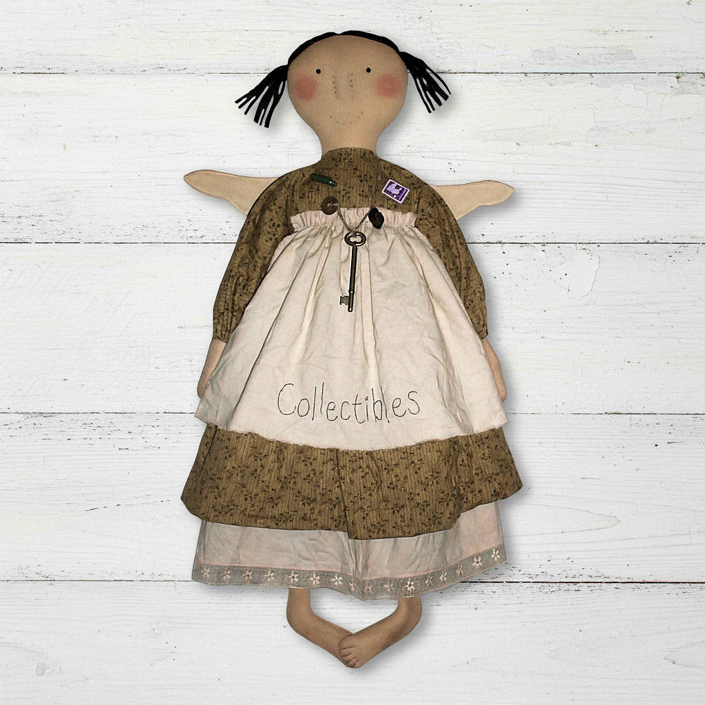 Textile doll with a brown dress and white apron on a wooden surface