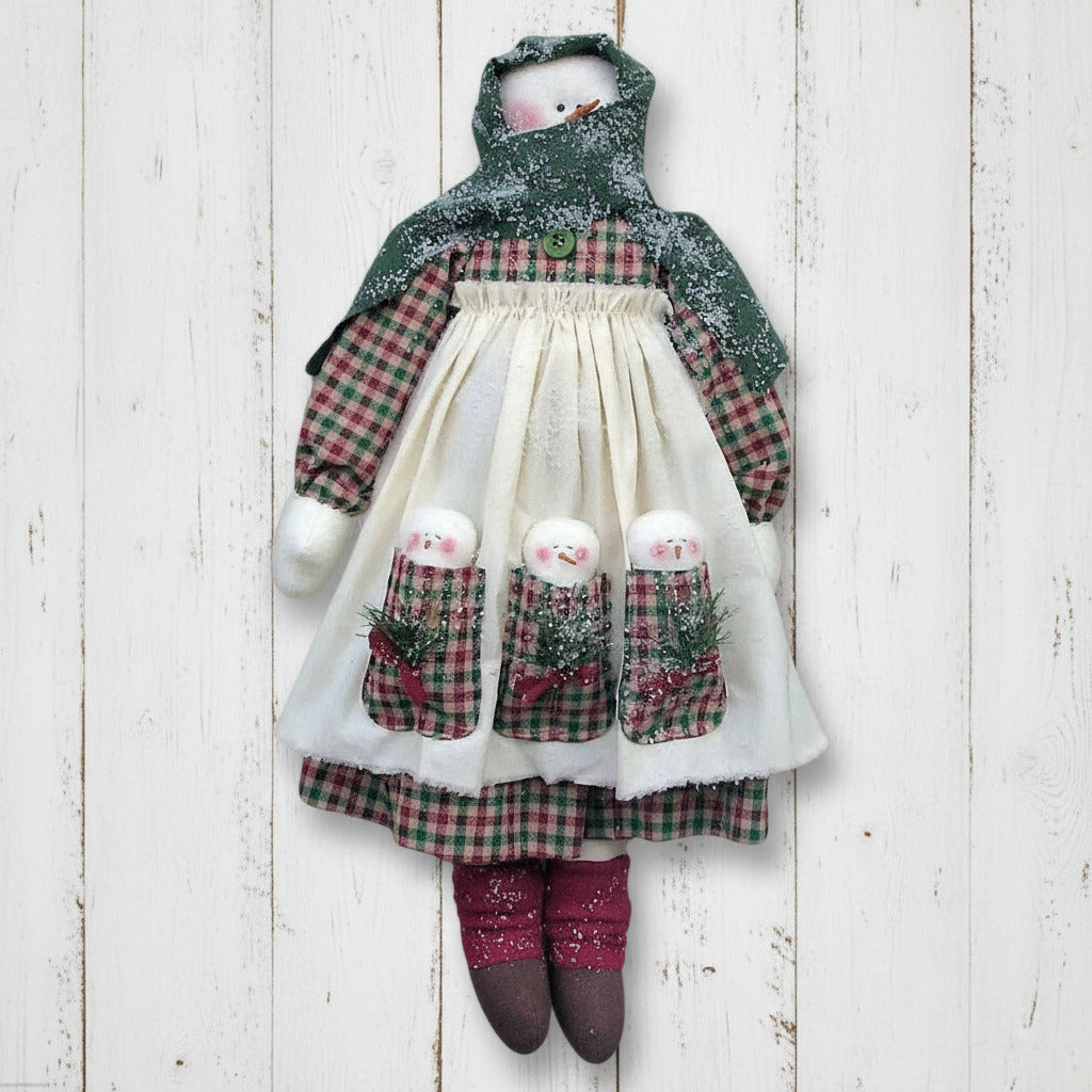 Decorative snowman doll wearing a plaid outfit with a white apron on a white background