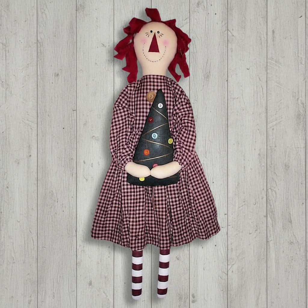 Vintage-style doll with red hair, checkered dress, and striped socks holding a black cone-shaped object on a wooden background.
