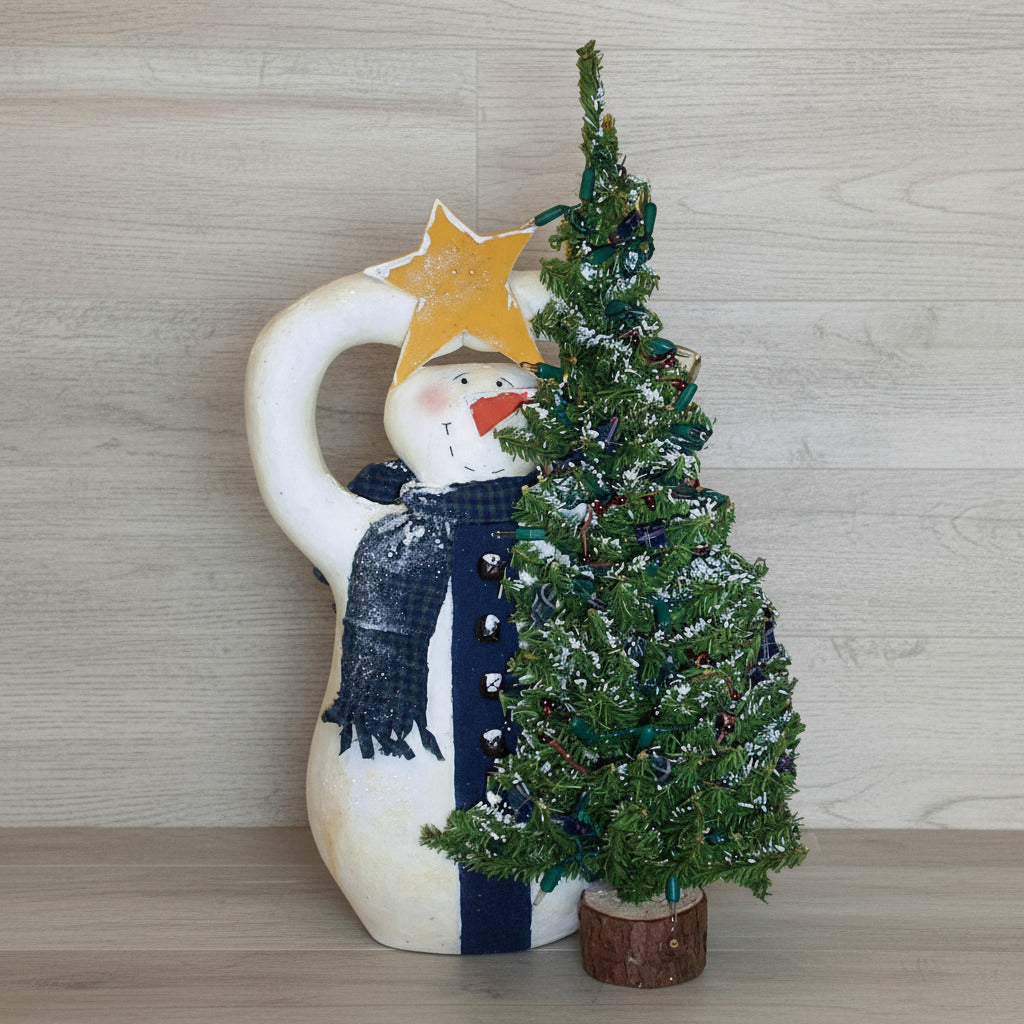 Decorative snowman placing a star atop small Christmas tree