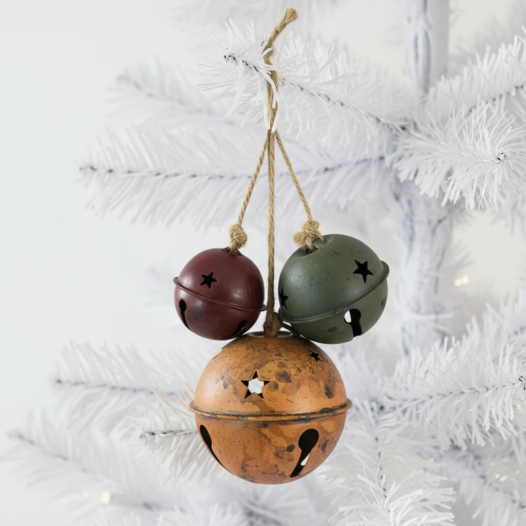Three distressed metal bells with star patterns hanging on a rope against a white background