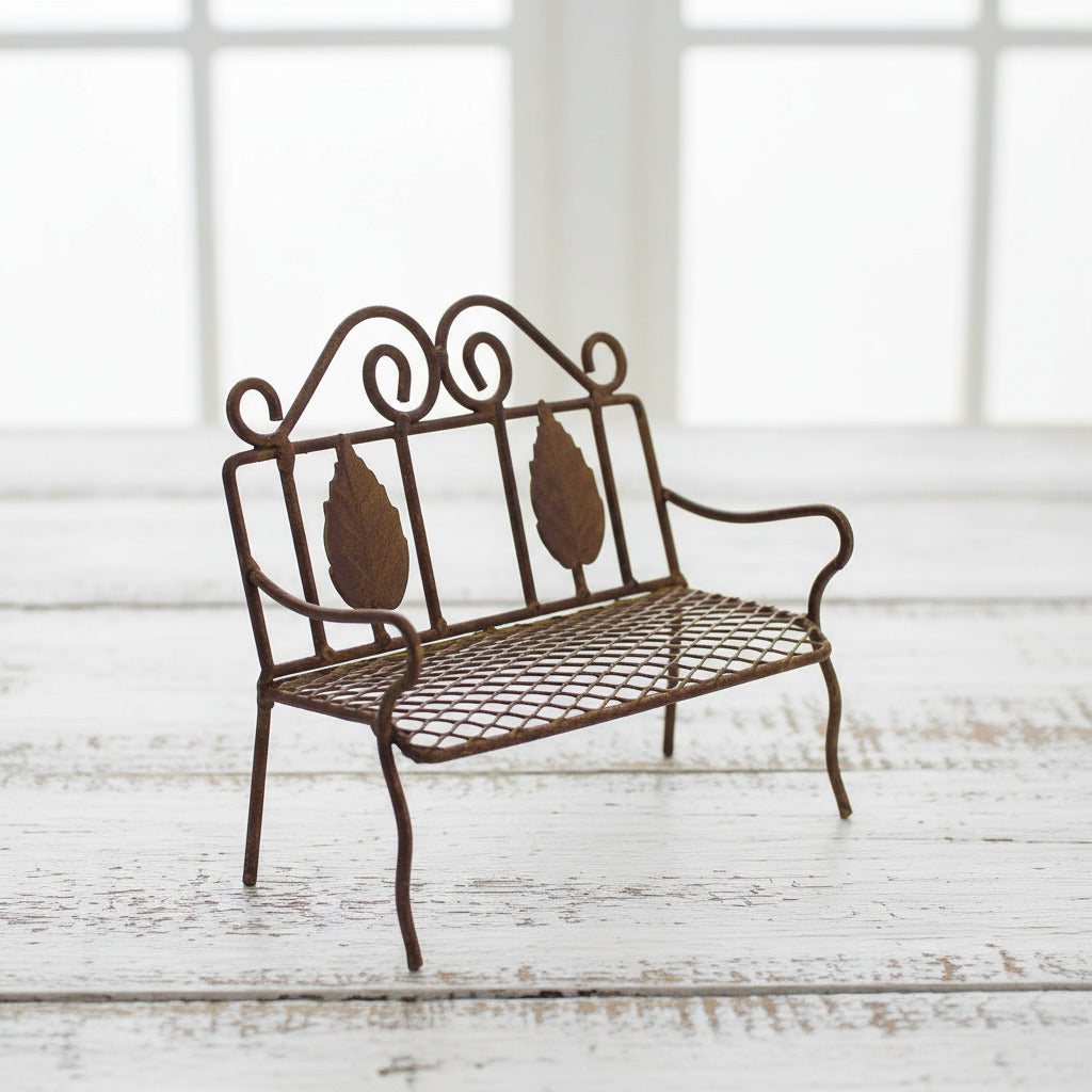 Decorative miniature rusty tin metal bench with intricate designs on a white background