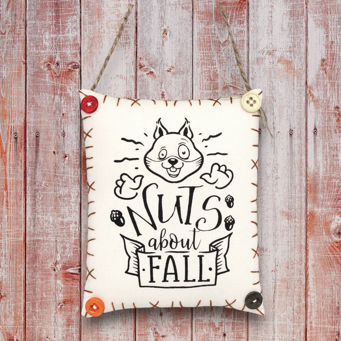 Decorative sign ornament with a squirrel design and 'Nuts about Fall' text on a wooden background