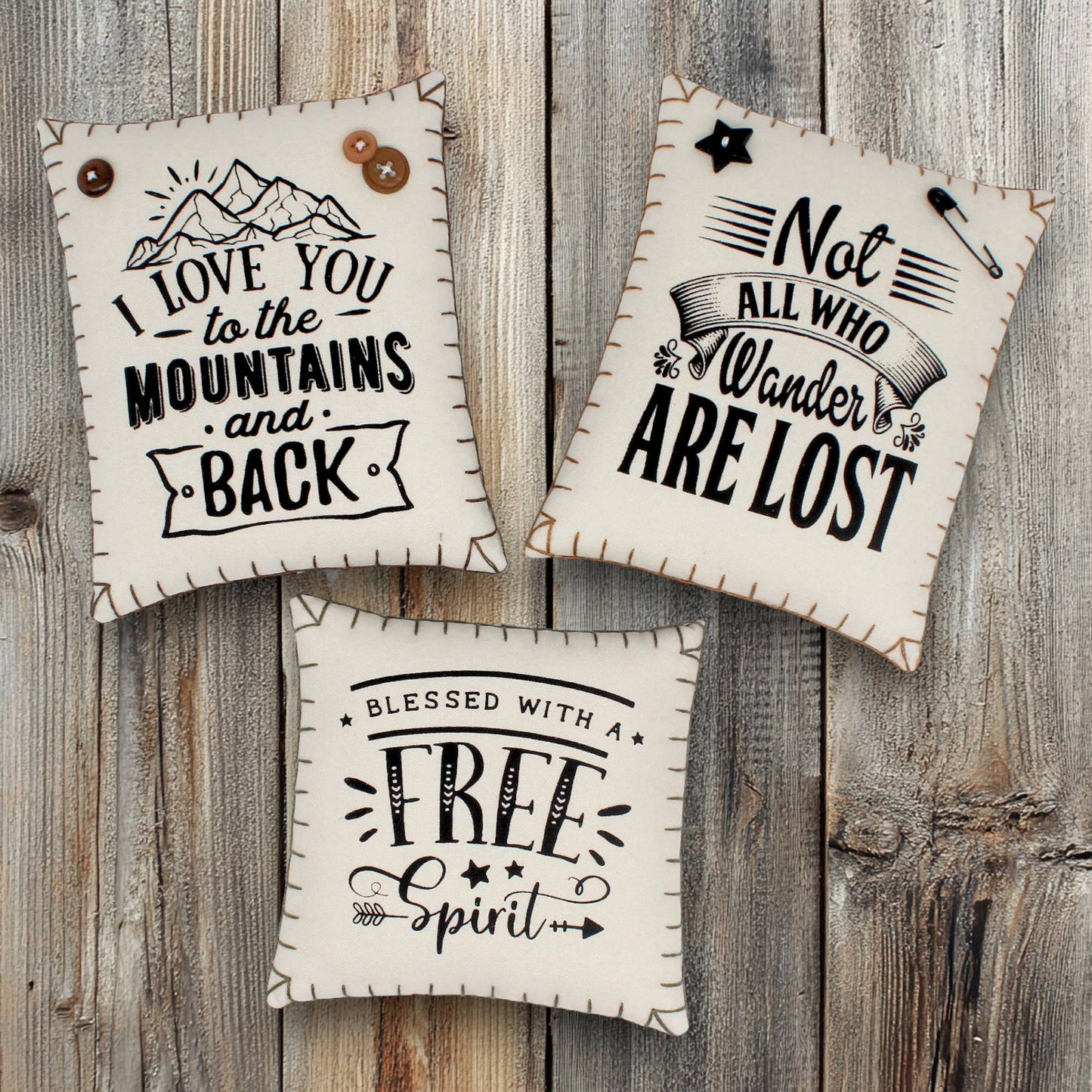 Three decorative handmade mini pillow bowl fillers screen-printed with motivational quotes about being in the mountains and having a wandering free spirit