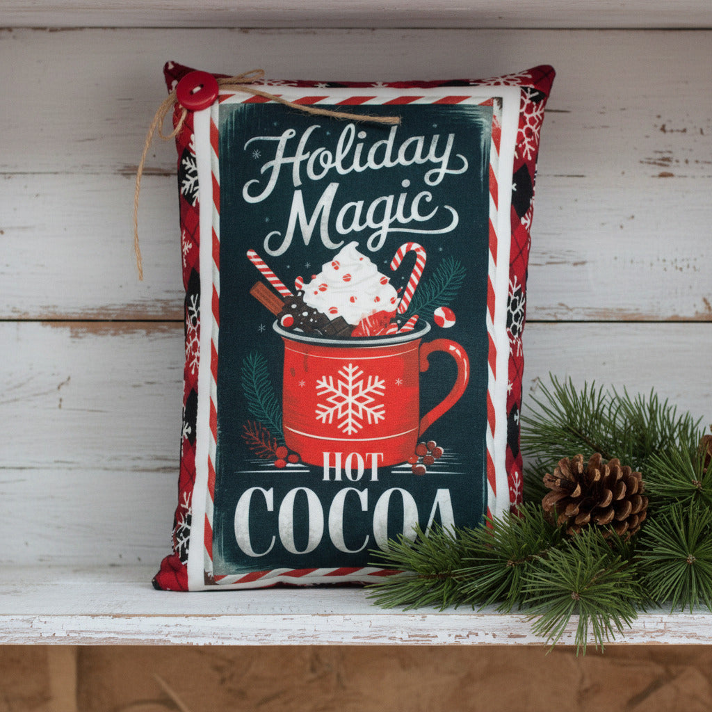 Decorative pillow with 'Holiday Magic Hot Cocoa' text and festive design on a white background