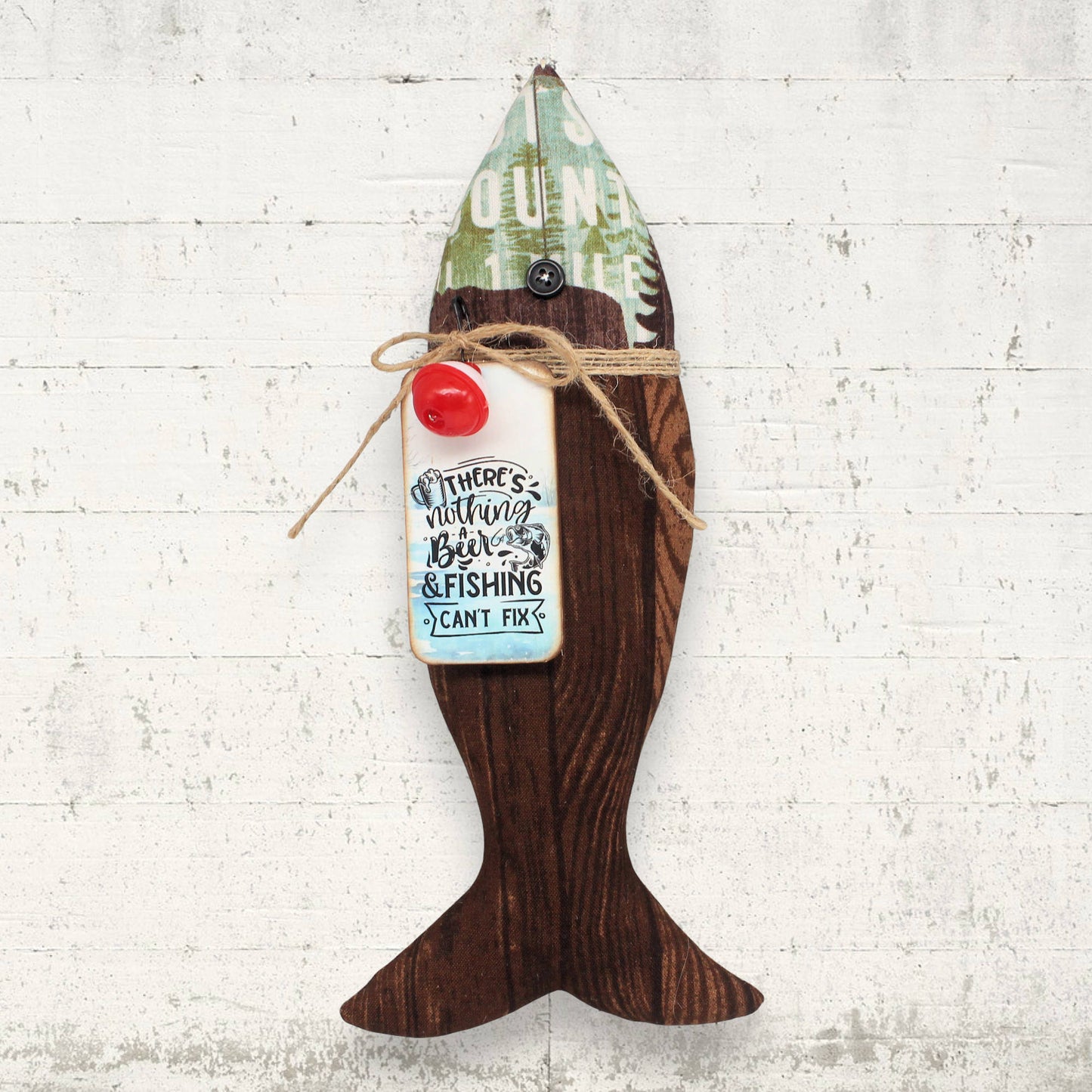 Fabric fish ornament with a tag on a white brick wall background