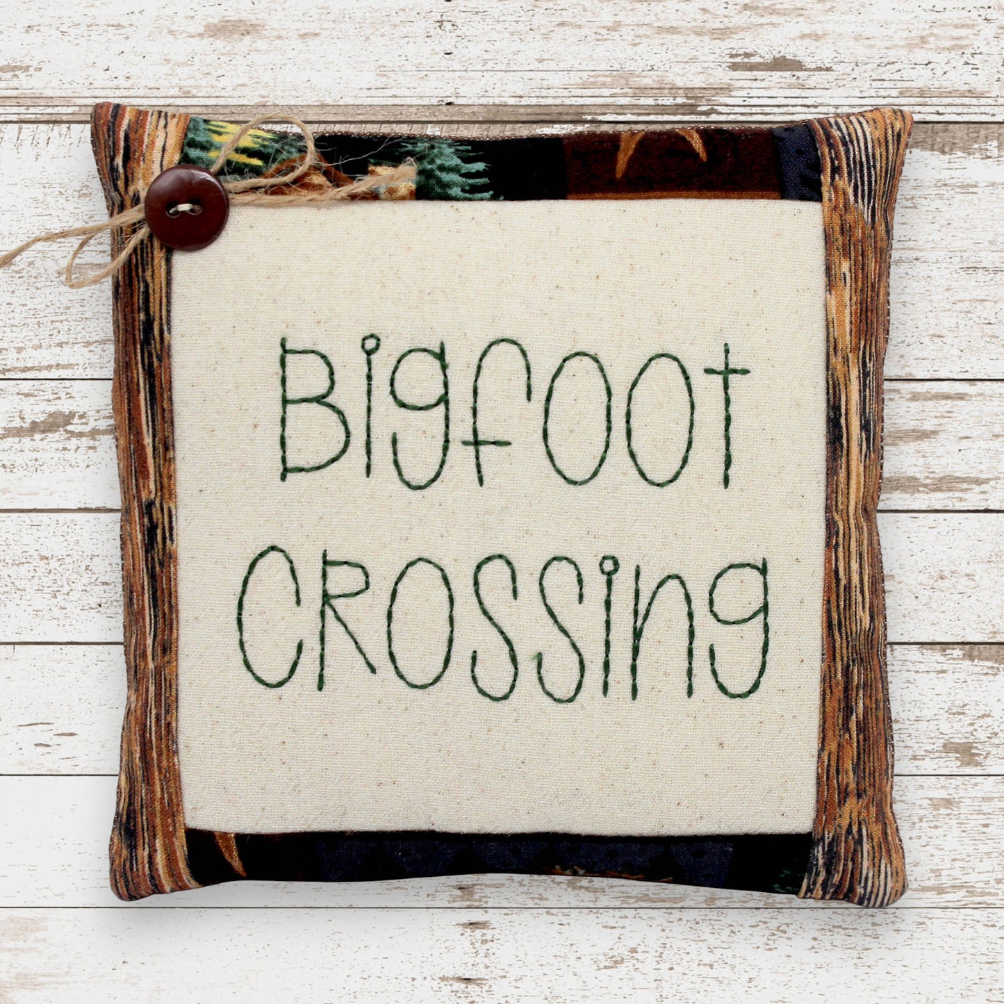 Decorative mini pillow embroidered with 'bigfoot crossing'