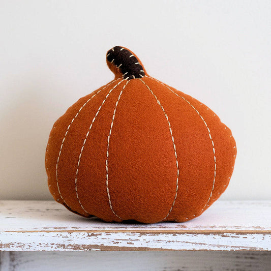 Fabric pumpkin on a wooden surface with a white background