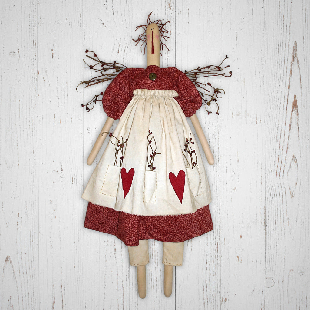 Handmade doll with a red and white dress featuring heart patterns on a white background