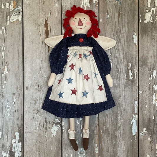 Vintage-style doll with red hair and star-patterned dress against a wooden background