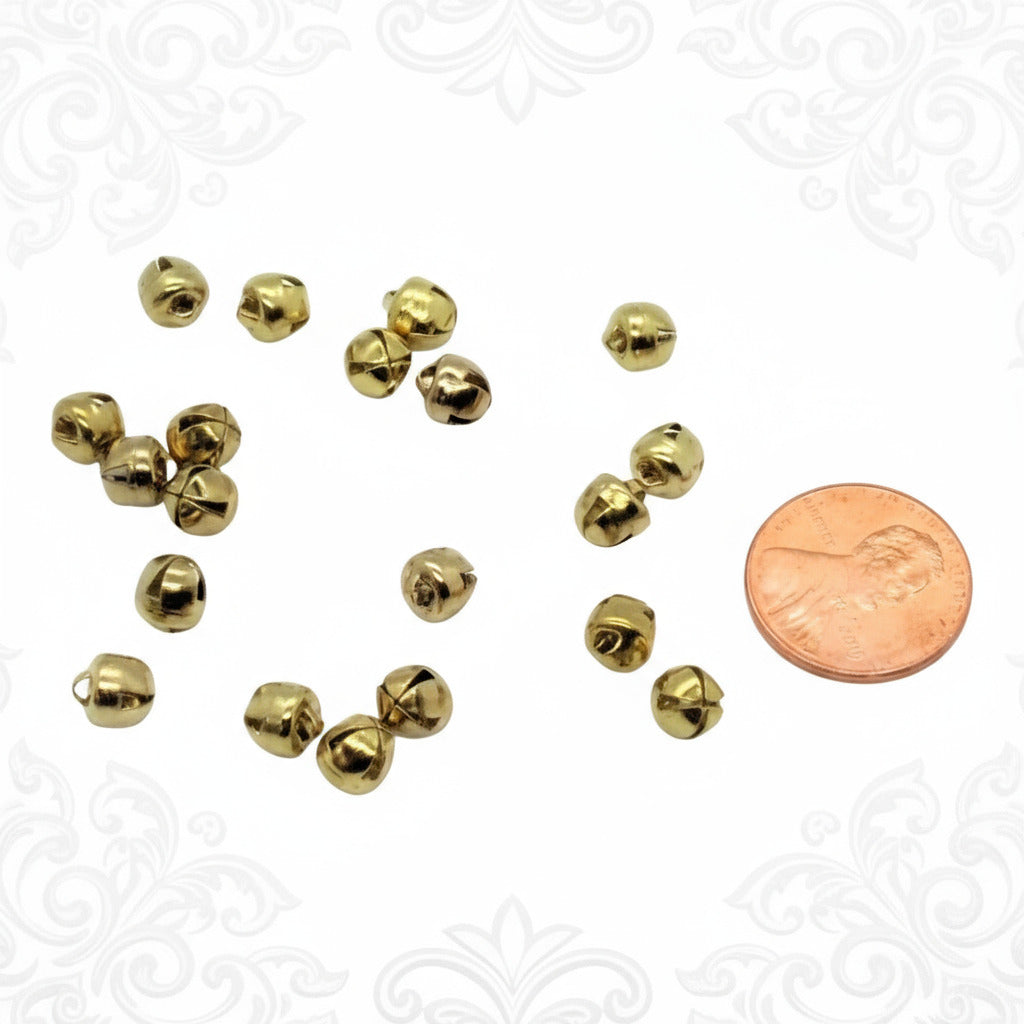 Gold jingle bells with a penny for size comparison on a white background
