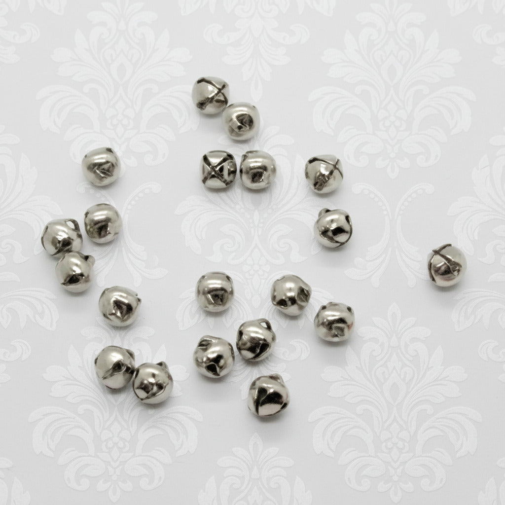 Silver metal jingle bells scattered on a white background