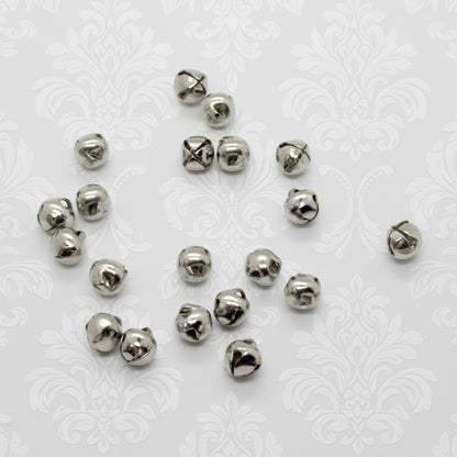 Silver metal jingle bells scattered on a white background
