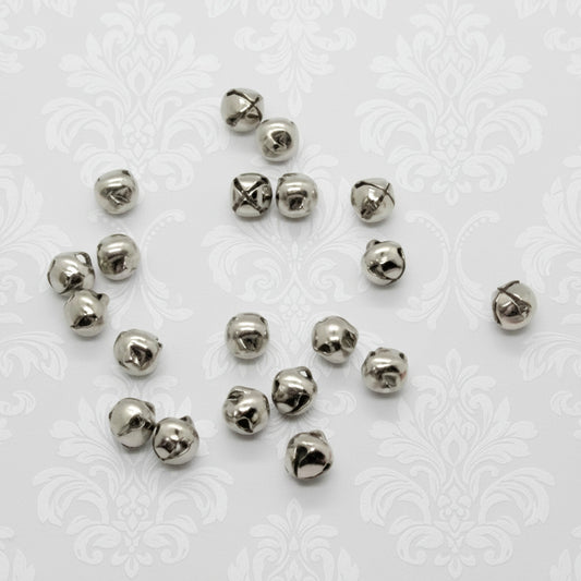 Silver metal jingle bells scattered on a white background