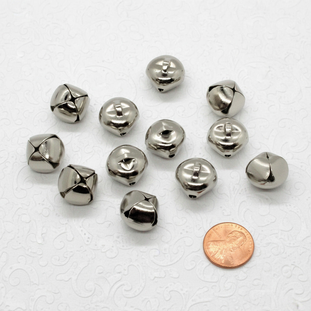 Silver jingle bells with a penny for scale on a white background