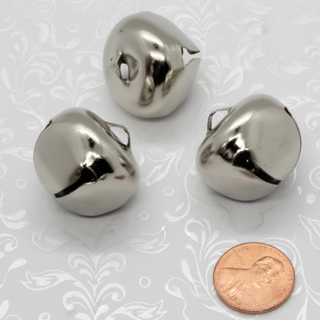 Three metallic bells with a penny for scale on a white background