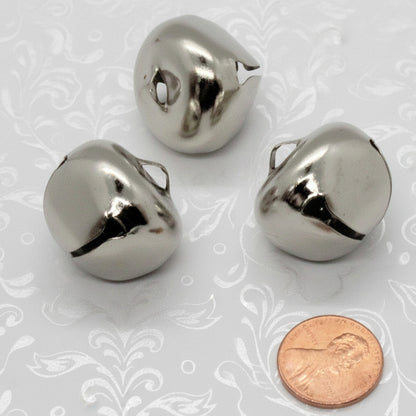 Three metallic bells with a penny for scale on a white background