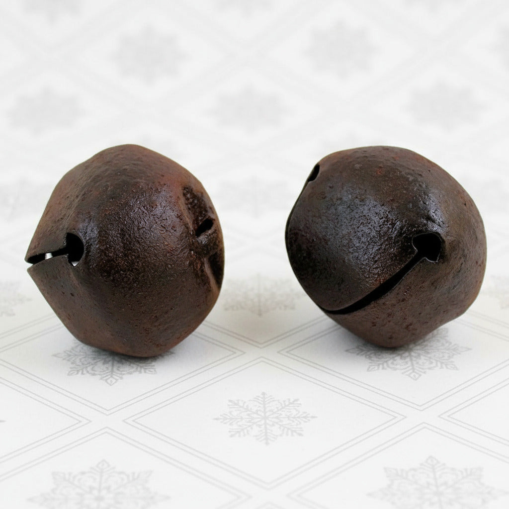 Two rustic metal bells on a white background