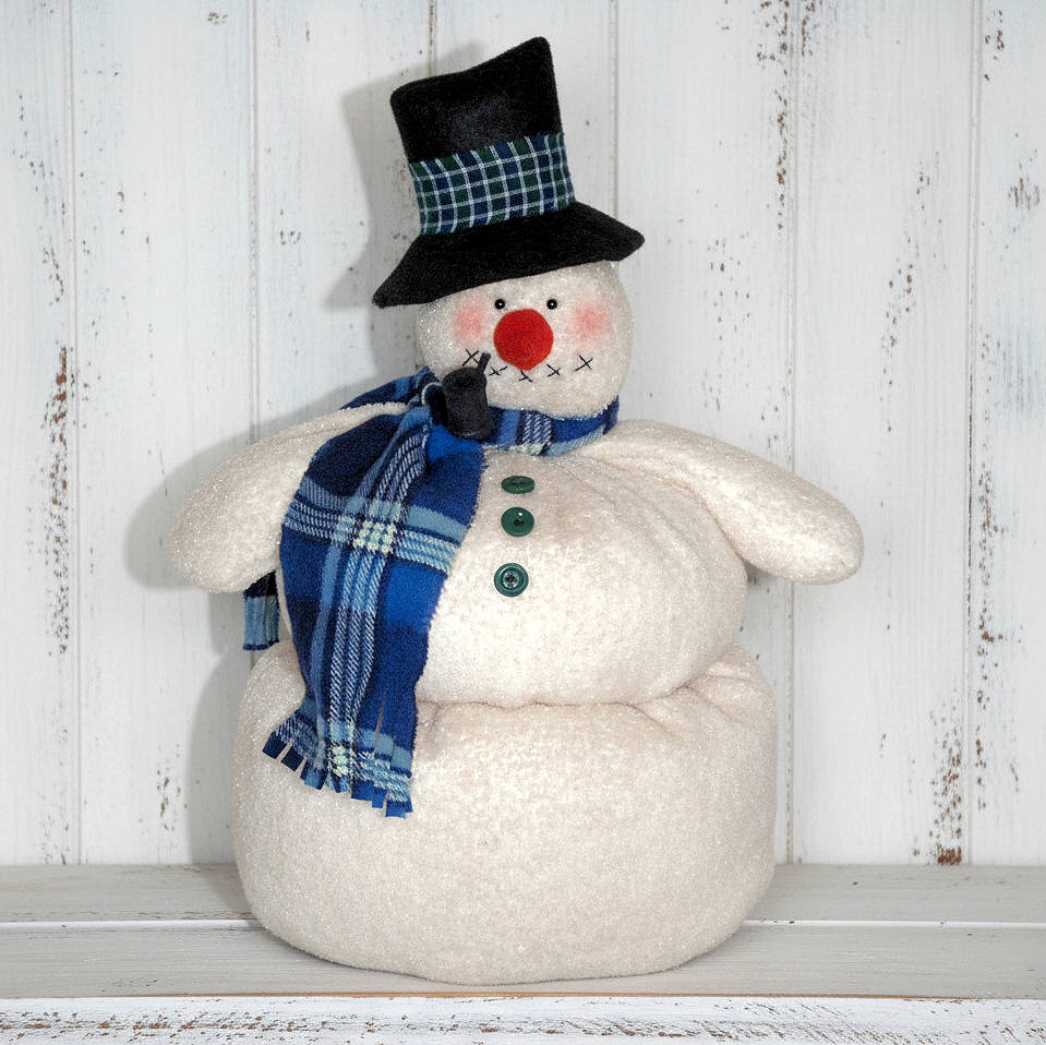 Snowman doll with a blue scarf and black top hat on a white wooden background