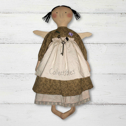 Textile doll with a brown dress and white apron on a wooden surface