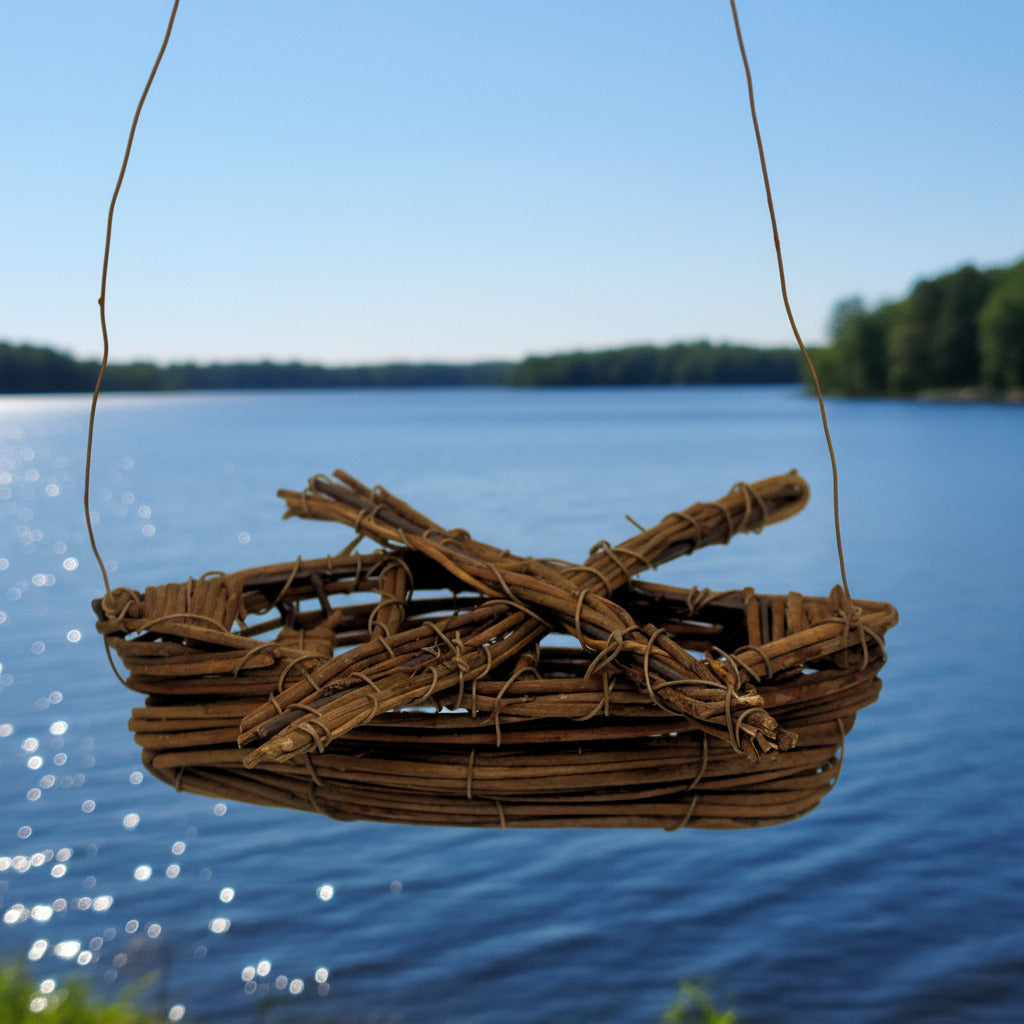 Woven boat model hanging over a body of water with trees in the background