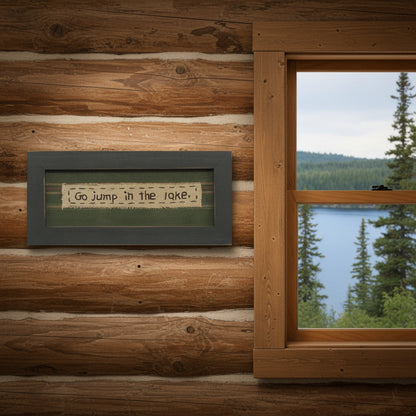 Wooden cabin interior with a framed quote and a window view of a lake and trees