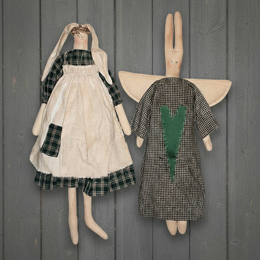 Two stuffed animal dolls with dresses against a wooden background