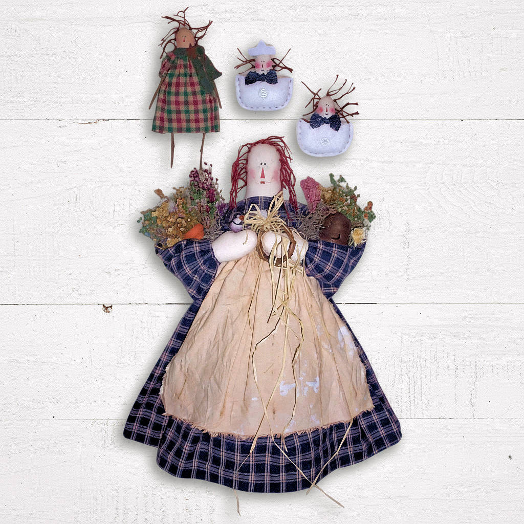 Decorative dolls with plaid dresses and floral arrangements on a white wooden background