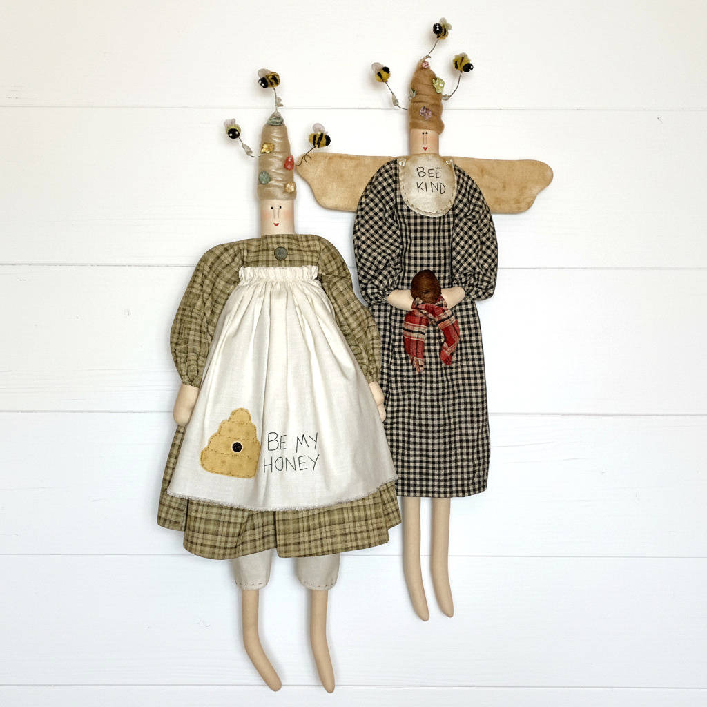 Two bee-themed dolls with dresses and scarves on a white wooden background