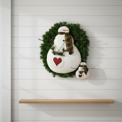 Decorative wreath with a snowman design on a white wall.