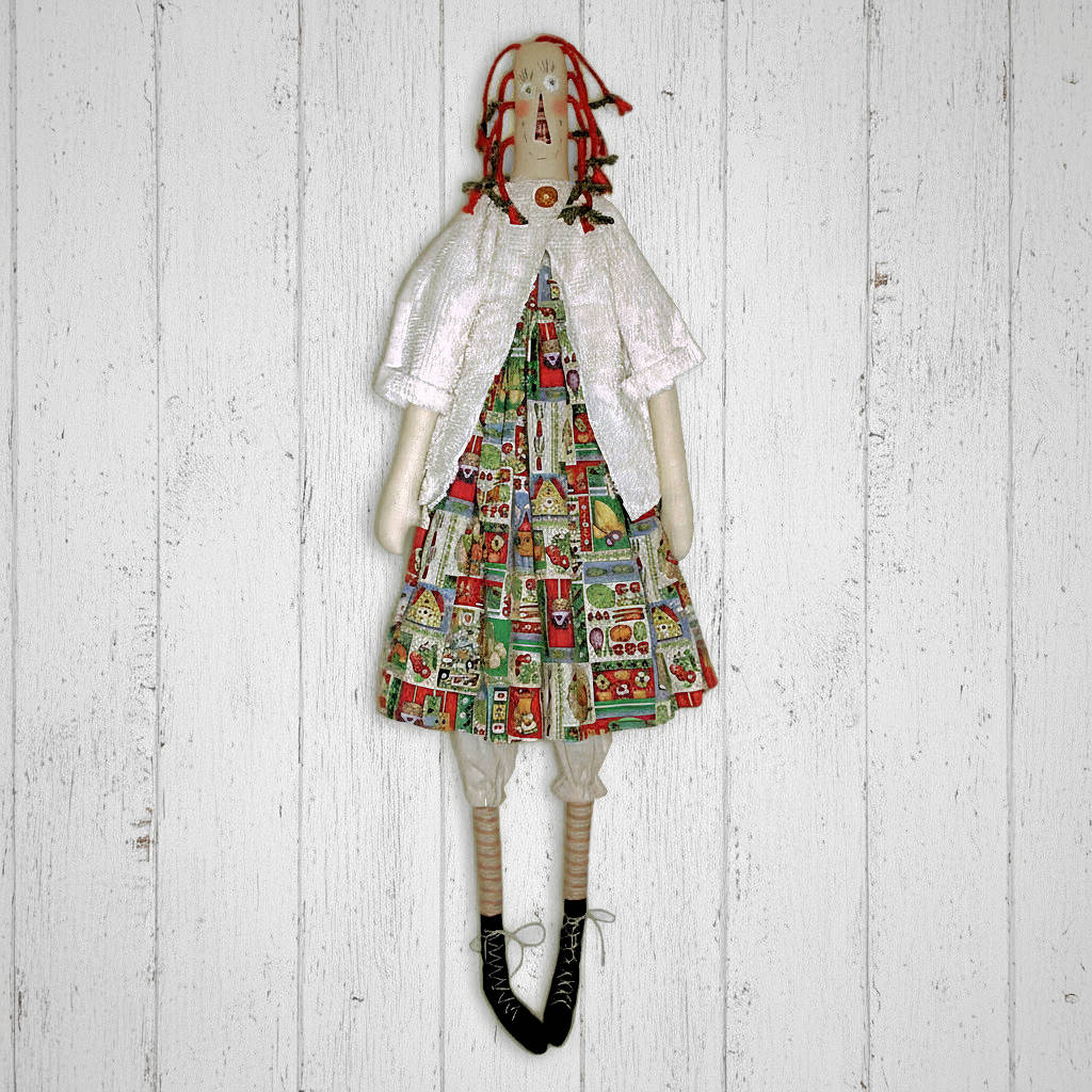 Textile doll wearing a colorful dress with a pattern on a wooden background