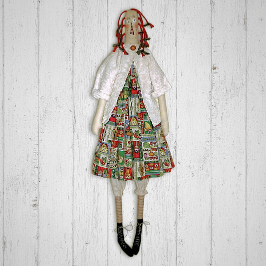 Textile doll wearing a colorful dress with a pattern on a wooden background