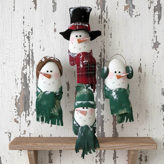 Set of four snowman shelf sitters with different accessories on a wooden shelf against a rustic white wall.