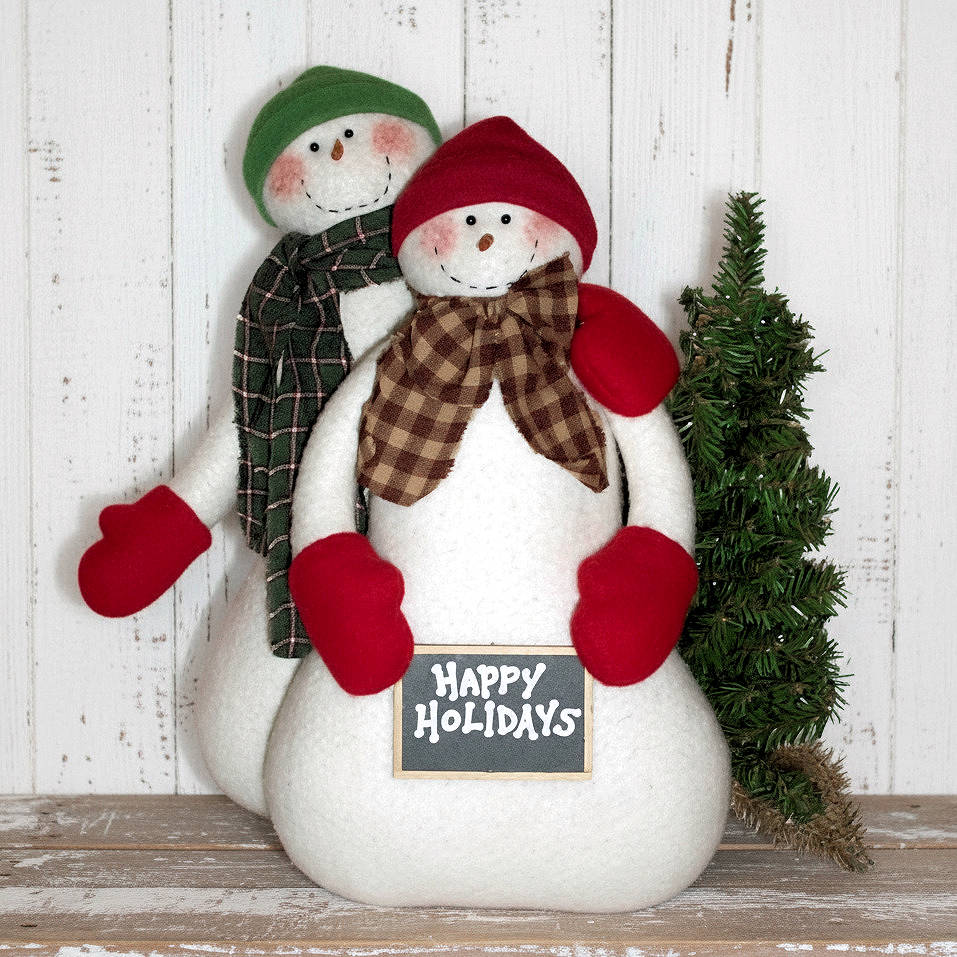 Two snowmen with a 'Happy Holidays' sign on a wooden surface with a white wooden background.