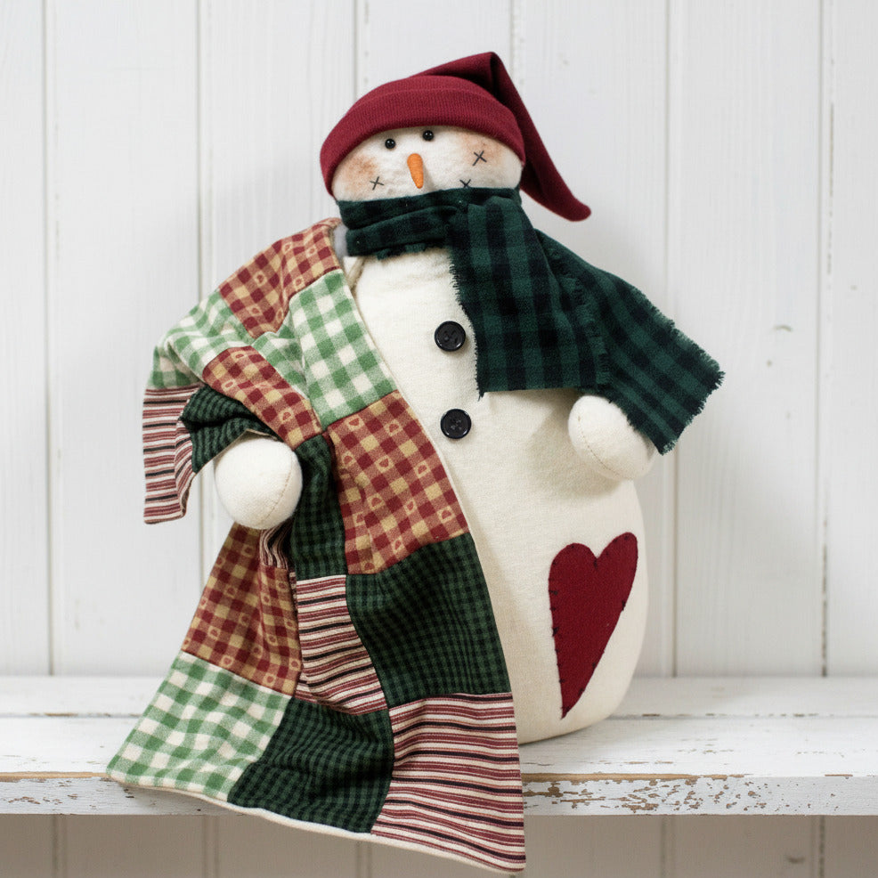 Decorative snowman figurine with a patchwork coat and red hat on a white background