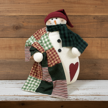 Decorative snowman with a patchwork coat and plaid scarf against a wooden background