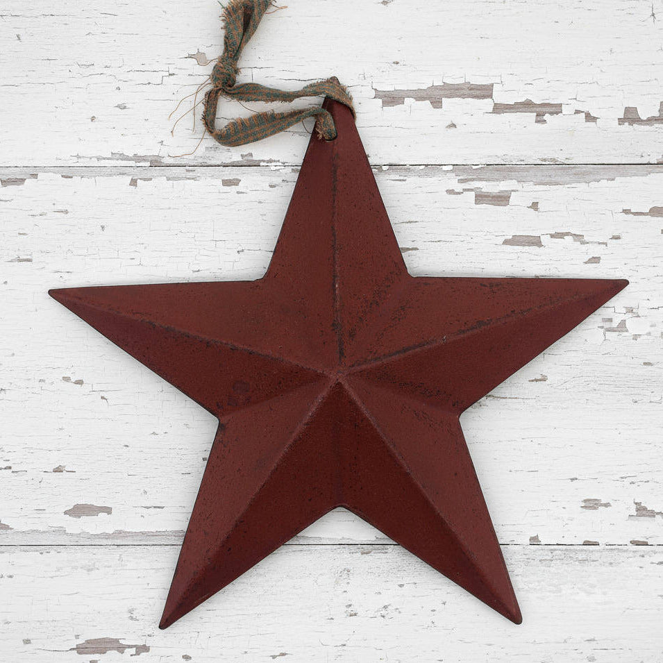 Red star-shaped metal ornament hanging on a white wooden surface