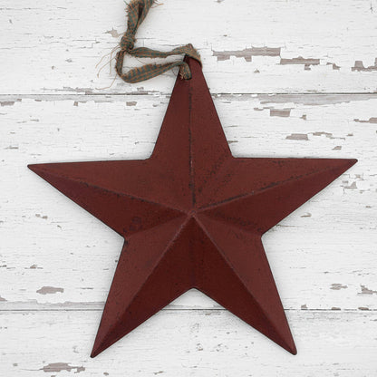 Red star-shaped metal ornament hanging on a white wooden surface