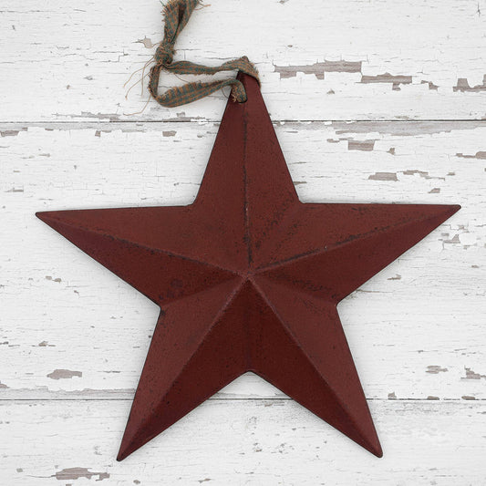 Red star-shaped metal ornament hanging on a white wooden surface