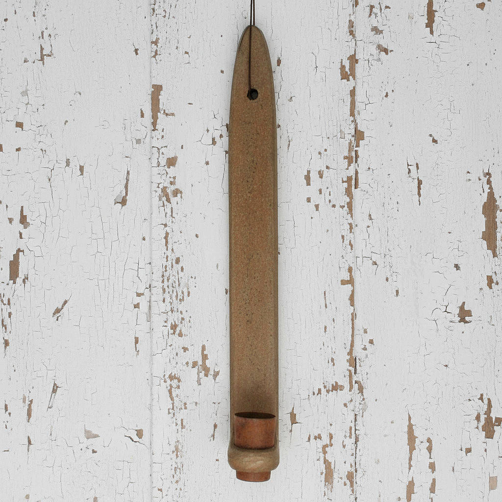 Wooden candle holder hanging on a distressed white wall