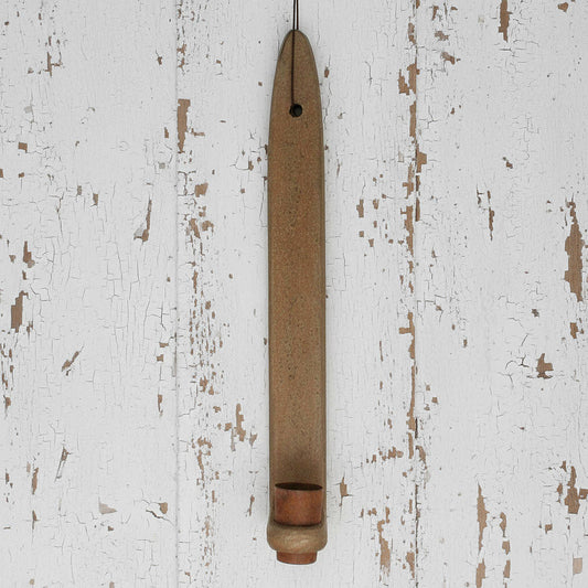 Wooden candle holder hanging on a distressed white wall