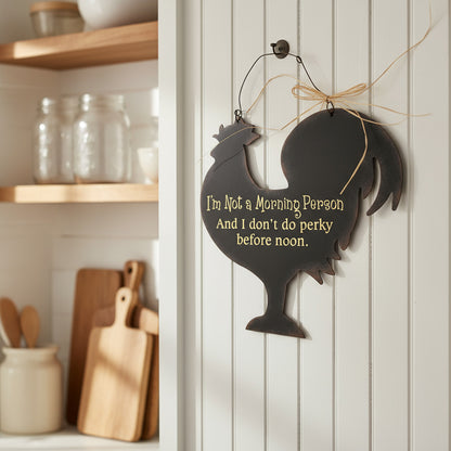 Decorative sign with rooster silhouette and humorous text in a kitchen setting