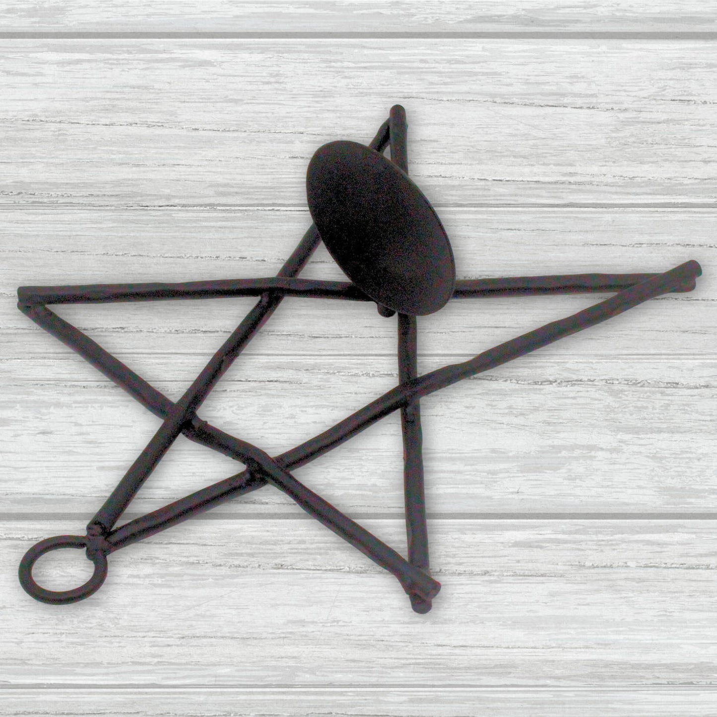Decorative black metal star-shaped candle holder on a light wooden surface