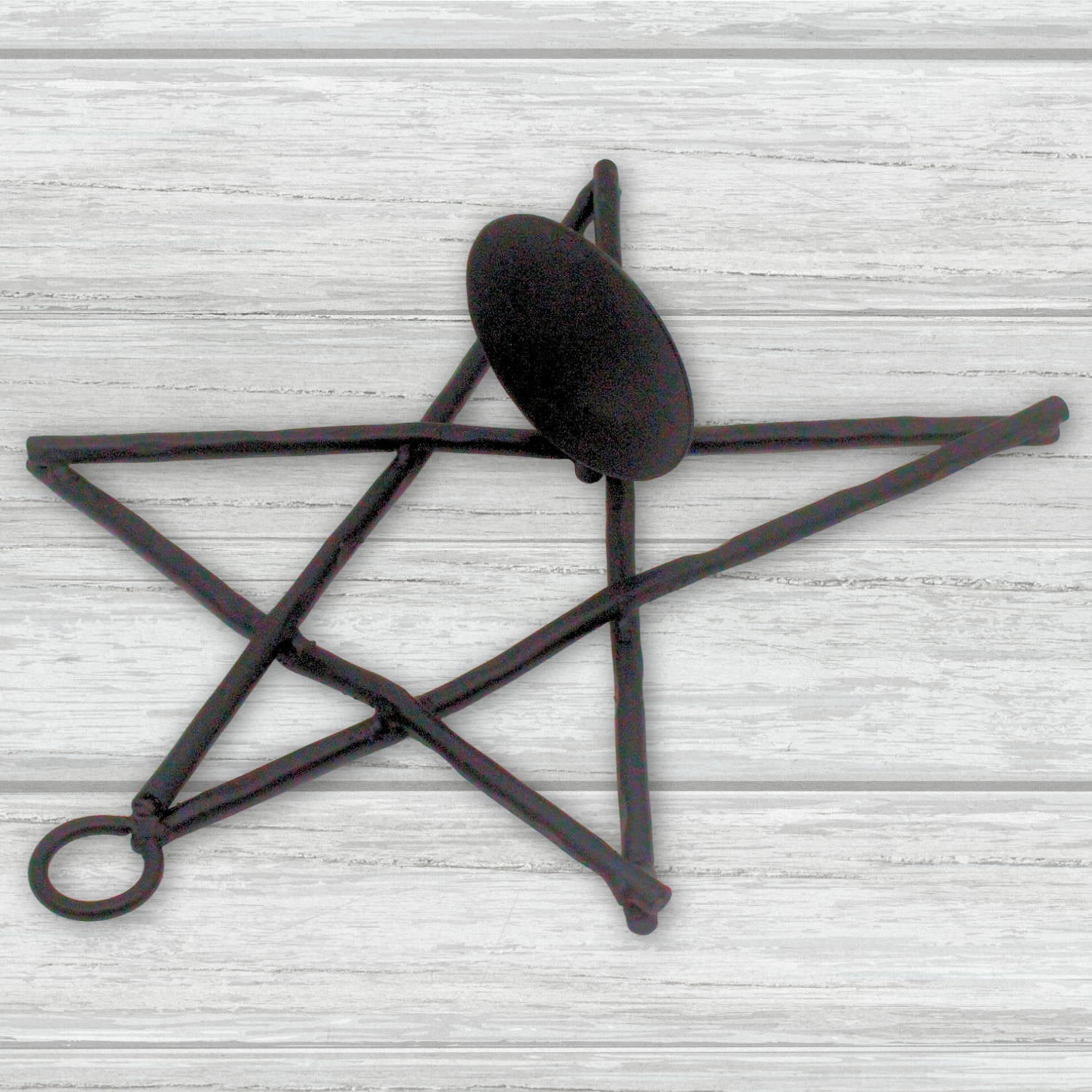 Decorative black metal star-shaped candle holder on a light wooden surface