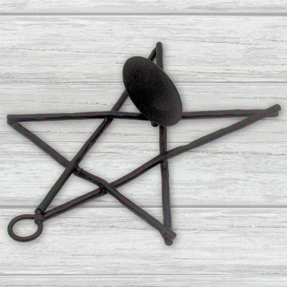 Decorative black metal star-shaped candle holder on a light wooden surface