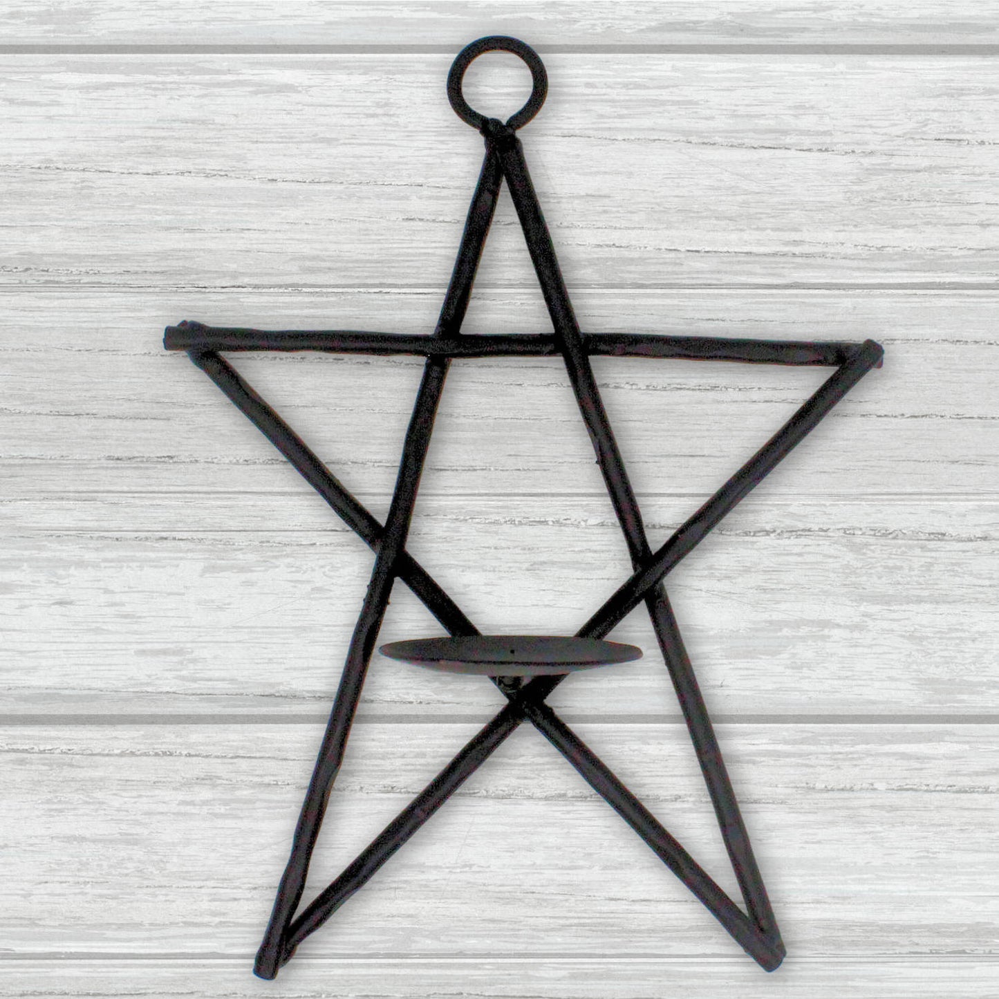 Black star-shaped candle holder on a light wooden background