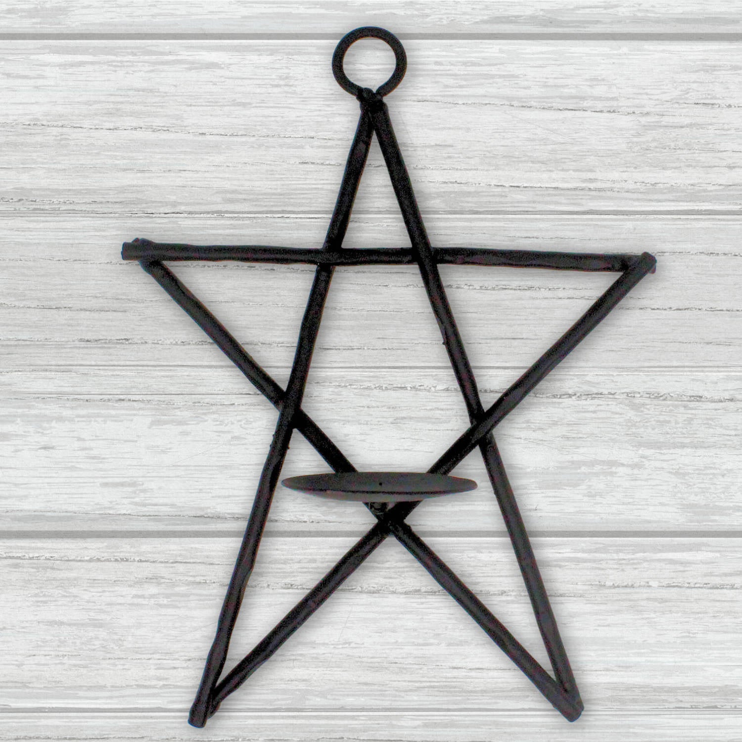 Black star-shaped candle holder on a light wooden background