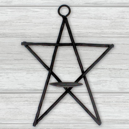 Black star-shaped candle holder on a light wooden background